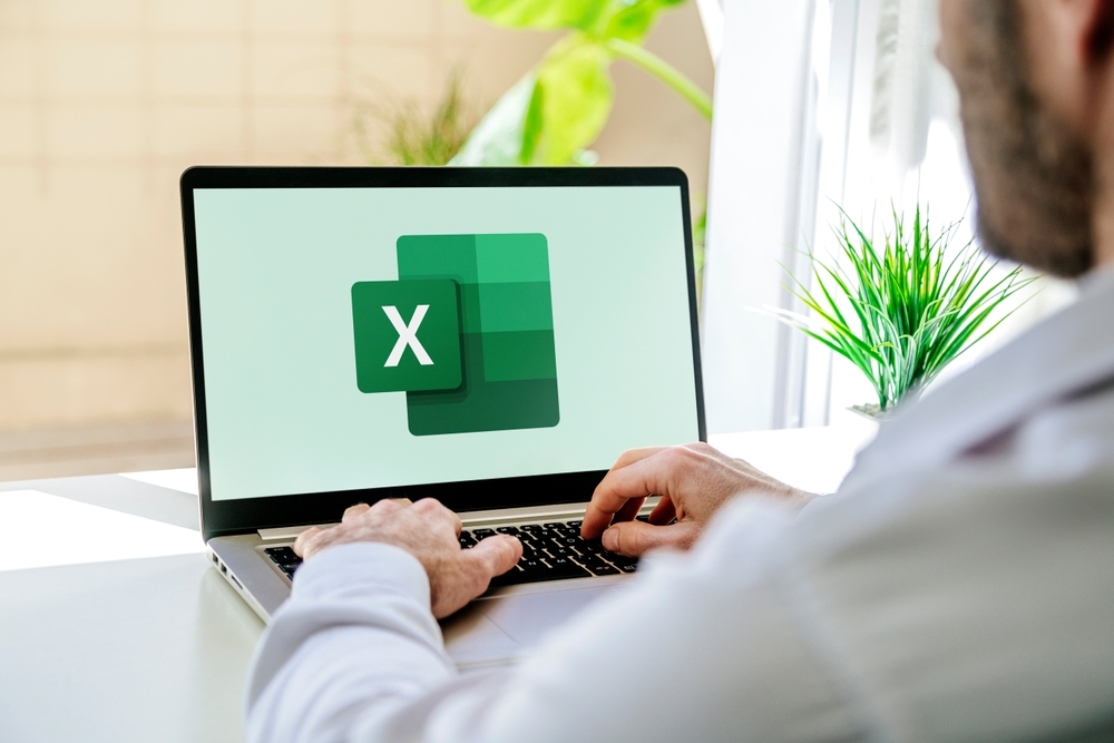 Man using a laptop computer displaying logo of Microsoft Excel on the screen. Spreadsheet software for calculate, formulas and productivity.