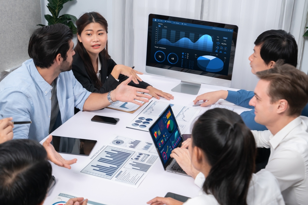 Analyst team utilizing BI Fintech to analyze financial data at table in meeting room. Businesspeople analyzing BI dashboard power for business insight and strategic marketing planning.